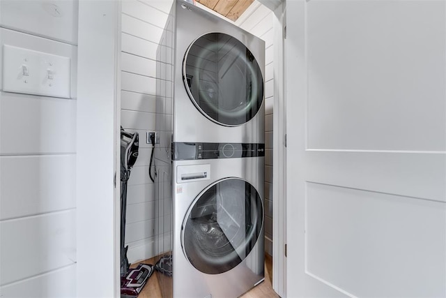 laundry room featuring stacked washer / dryer, wood finished floors, and laundry area