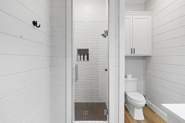 full bathroom with wooden walls, wood finished floors, toilet, and a stall shower
