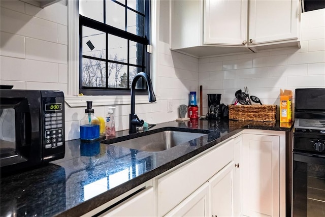 kitchen with white cabinetry, dark stone counters, sink, and tasteful backsplash