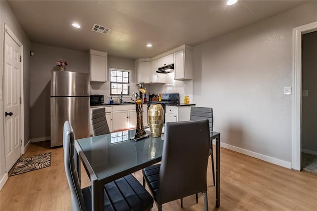 dining space with sink and light hardwood / wood-style flooring