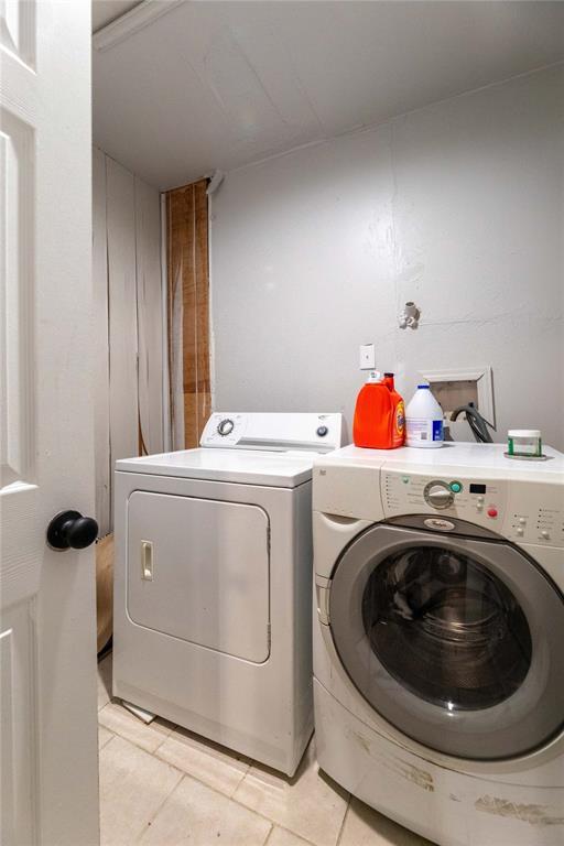 washroom featuring light tile patterned floors and washer and clothes dryer