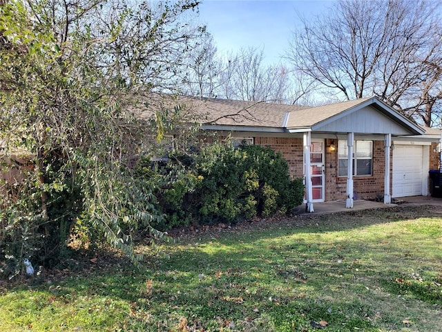 view of front of house with an attached garage, a front yard, and brick siding