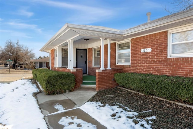 snow covered property entrance with a porch