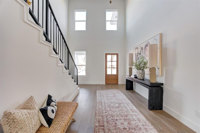 foyer entrance with plenty of natural light, a towering ceiling, and light hardwood / wood-style flooring