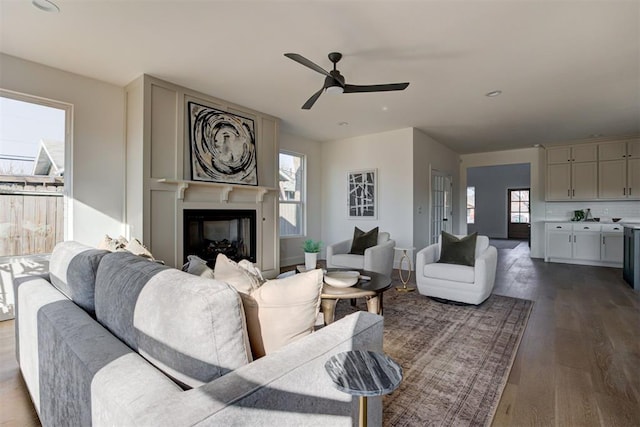 living room with ceiling fan, a large fireplace, and wood-type flooring