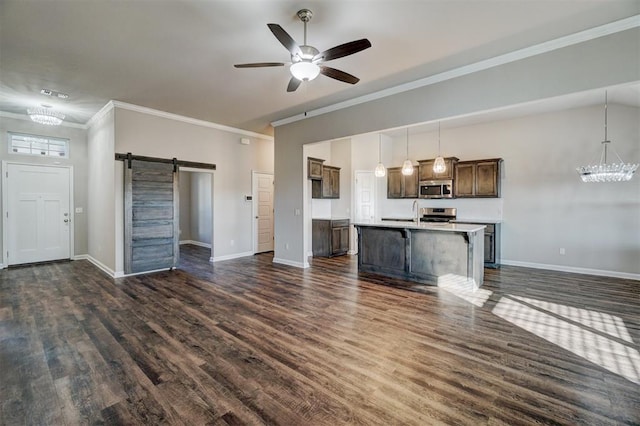 unfurnished living room featuring ceiling fan with notable chandelier, sink, a barn door, ornamental molding, and dark hardwood / wood-style flooring