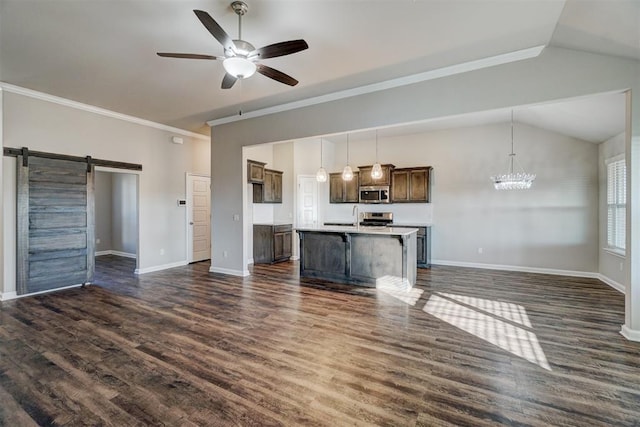 unfurnished living room featuring ornamental molding, ceiling fan with notable chandelier, vaulted ceiling, dark wood-type flooring, and a barn door