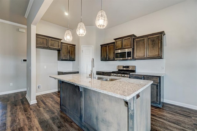 kitchen with a kitchen island with sink, sink, hanging light fixtures, light stone countertops, and stainless steel appliances