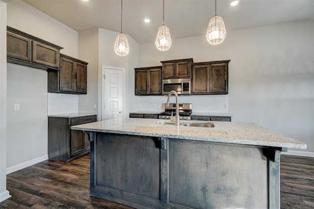 kitchen with pendant lighting, a center island with sink, light stone countertops, and sink