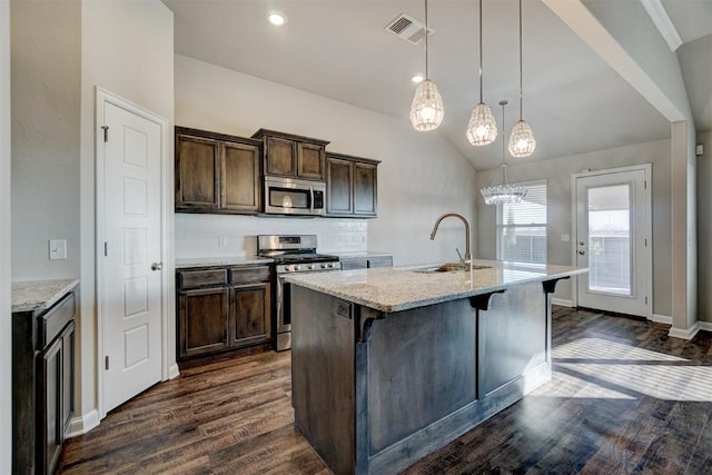 kitchen with pendant lighting, sink, light stone countertops, appliances with stainless steel finishes, and tasteful backsplash