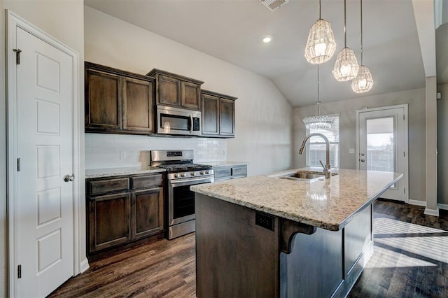 kitchen featuring decorative backsplash, dark brown cabinetry, stainless steel appliances, a kitchen island with sink, and hanging light fixtures