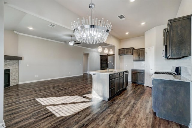 kitchen featuring a center island with sink, ceiling fan with notable chandelier, pendant lighting, and dark wood-type flooring