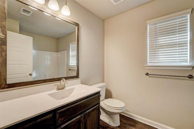 bathroom featuring hardwood / wood-style flooring, vanity, toilet, and walk in shower