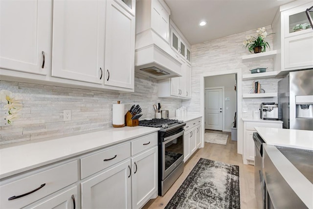 kitchen with white cabinets, custom range hood, backsplash, and stainless steel appliances