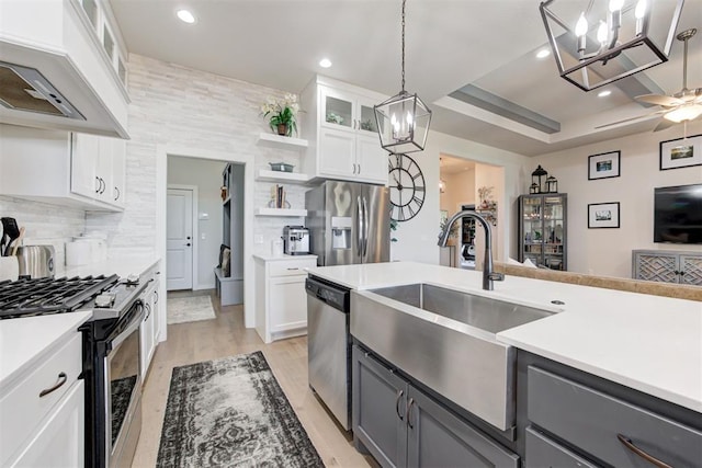 kitchen featuring stainless steel appliances, a tray ceiling, sink, gray cabinets, and white cabinetry