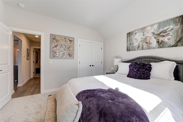 bedroom with light colored carpet, a closet, and lofted ceiling