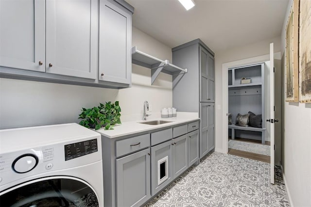 clothes washing area with sink, light tile patterned floors, cabinets, and washer / dryer