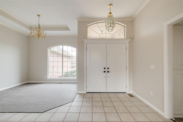 foyer entrance with ornamental molding, a chandelier, a raised ceiling, and light tile patterned floors