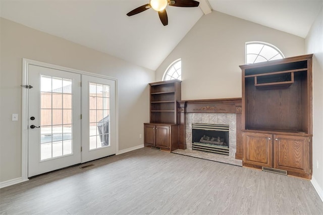 unfurnished living room featuring ceiling fan, lofted ceiling, a tile fireplace, and light hardwood / wood-style flooring