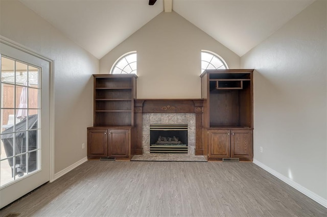 unfurnished living room with vaulted ceiling with beams, a wealth of natural light, a fireplace, and light hardwood / wood-style flooring