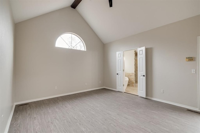 unfurnished room with wood-type flooring and lofted ceiling with beams