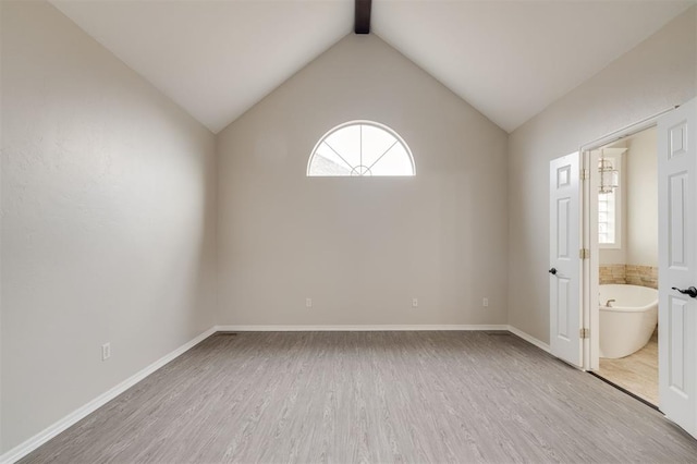 spare room featuring vaulted ceiling with beams and light hardwood / wood-style flooring