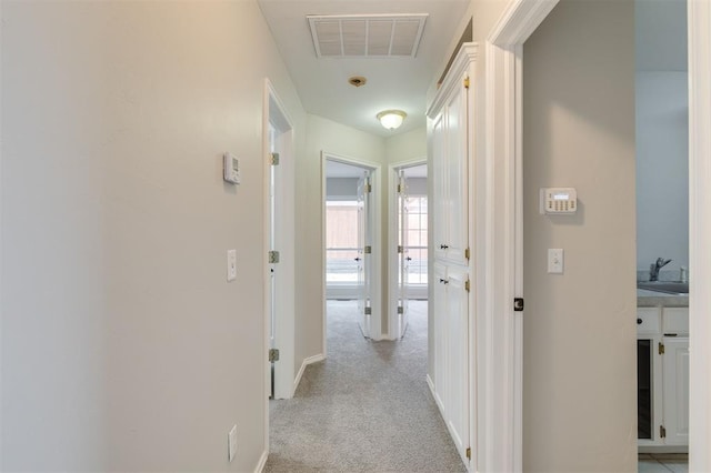 hall with light colored carpet and sink