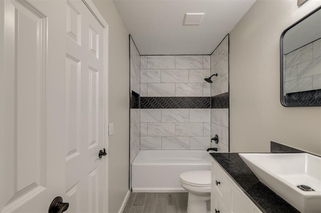 full bathroom featuring vanity, tiled shower / bath combo, and toilet