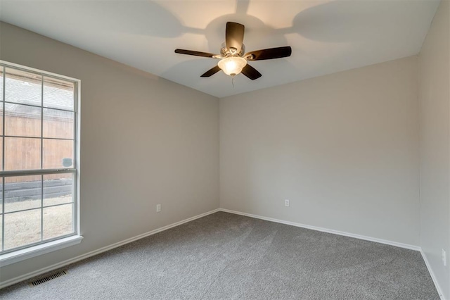 spare room with ceiling fan, plenty of natural light, and carpet