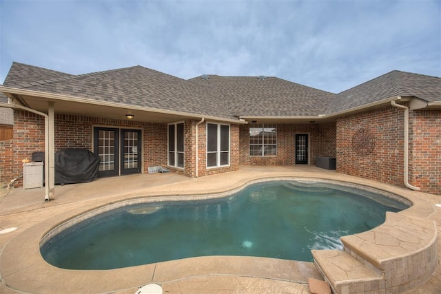 view of pool with french doors, area for grilling, and a patio area