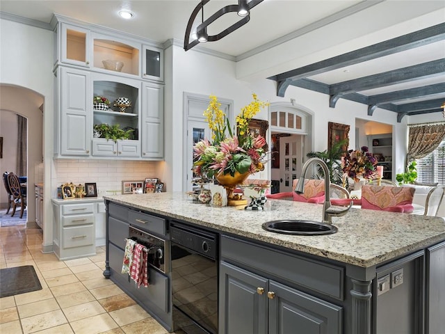 5808 Mistletoe Ct, Oklahoma City, OK 73142 - kitchen with decorative backsplash, gray cabinetry, sink, a center island with sink, and beamed ceiling