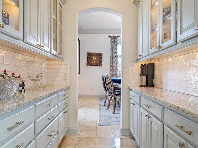 5808 Mistletoe Ct, Oklahoma City, OK 73142 - kitchen with backsplash, crown molding, light tile patterned floors, and light stone countertops