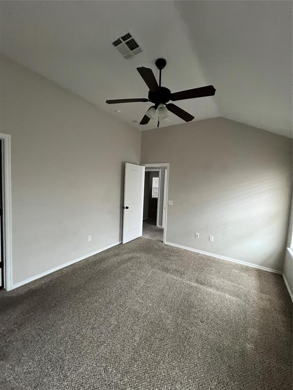 unfurnished room featuring ceiling fan, dark carpet, and vaulted ceiling