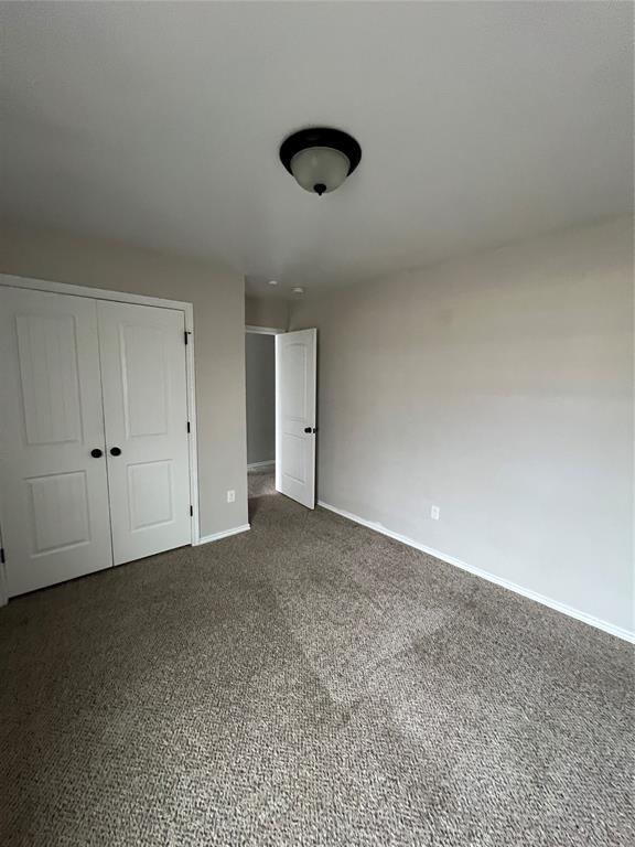 unfurnished bedroom featuring dark carpet and a closet