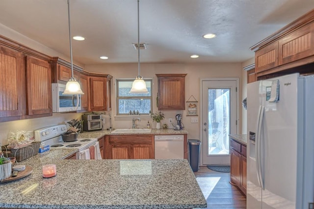 kitchen featuring sink, white appliances, dark hardwood / wood-style flooring, decorative light fixtures, and kitchen peninsula