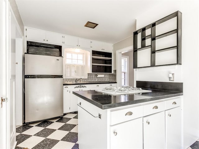 kitchen featuring stainless steel fridge, white gas cooktop, white cabinets, and plenty of natural light