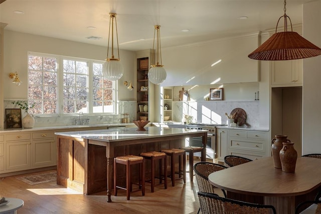 kitchen featuring light wood-type flooring, tasteful backsplash, a kitchen island, and hanging light fixtures