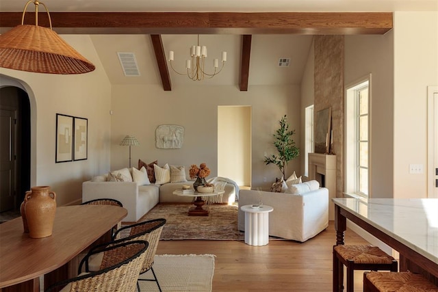 living room featuring vaulted ceiling with beams, light hardwood / wood-style floors, a wealth of natural light, and a chandelier