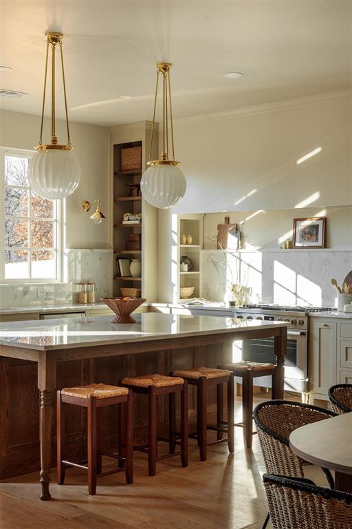 kitchen with light hardwood / wood-style floors, a kitchen bar, hanging light fixtures, and tasteful backsplash