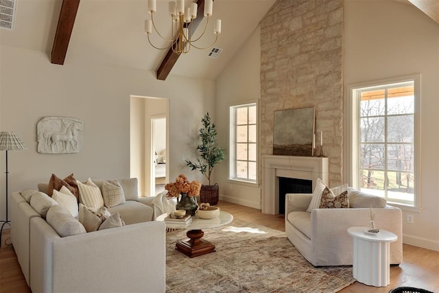 living room featuring wood-type flooring, beam ceiling, high vaulted ceiling, a fireplace, and a chandelier