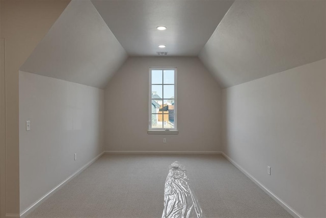 additional living space featuring light colored carpet and vaulted ceiling