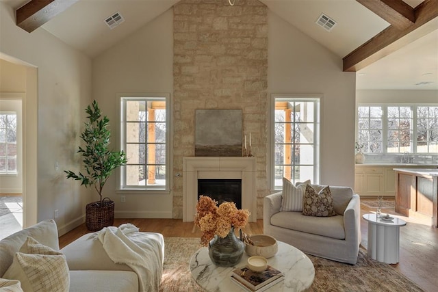 living room with light hardwood / wood-style floors, high vaulted ceiling, beamed ceiling, and sink