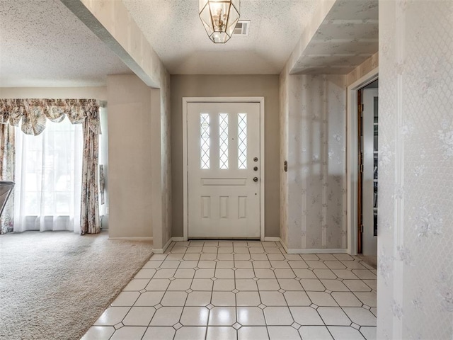 carpeted entryway featuring a healthy amount of sunlight and a textured ceiling