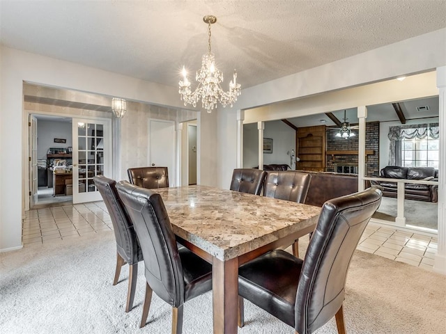 carpeted dining room with a fireplace, a textured ceiling, and ceiling fan with notable chandelier