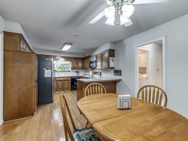 dining area with ceiling fan, light hardwood / wood-style floors, washer / dryer, and a textured ceiling