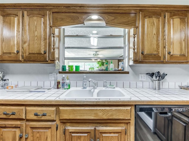 kitchen featuring tile countertops, dishwashing machine, and sink