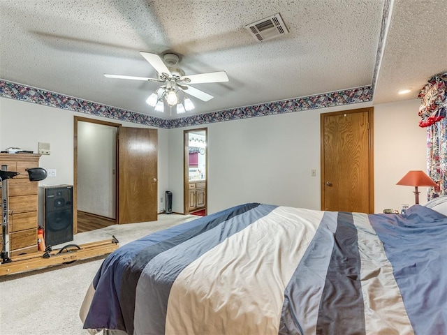 bedroom featuring a textured ceiling, carpet floors, ensuite bath, and ceiling fan