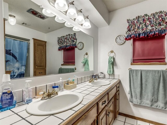 bathroom with a textured ceiling, vanity, and tile patterned floors