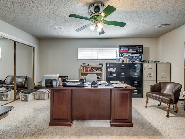 carpeted office featuring ceiling fan and a textured ceiling