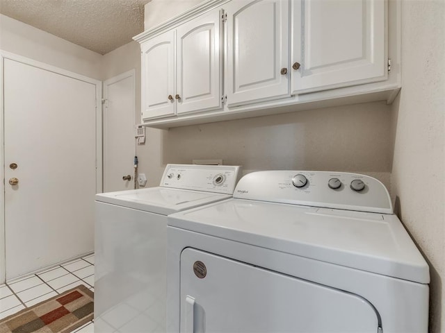 laundry room with cabinets, independent washer and dryer, a textured ceiling, and light tile patterned floors